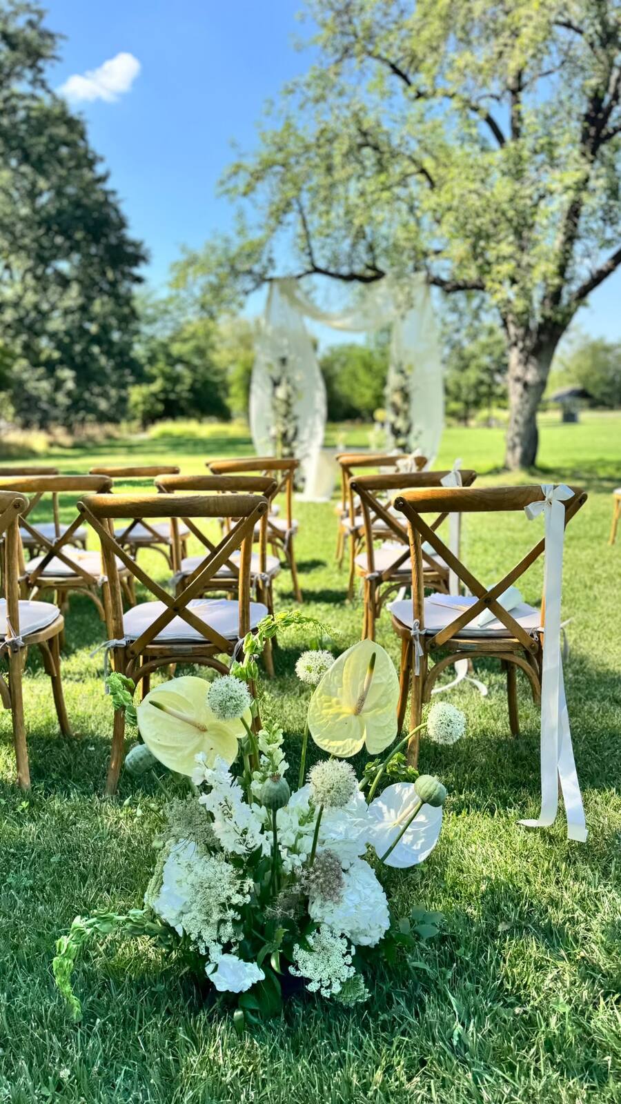 Rows of ceremony seating leading to a draped floral arch