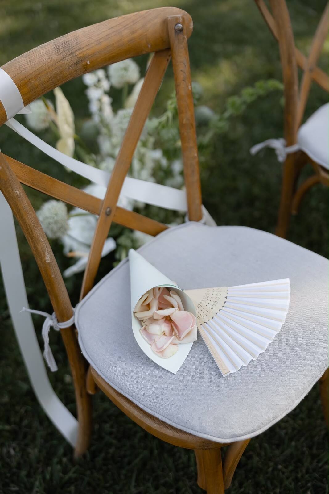 A ceremony chair styled with a petal cone and hand fan